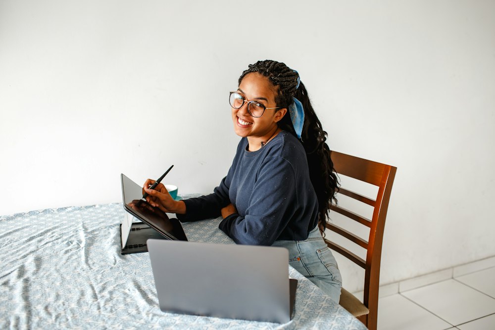Mulher sorrindo enquanto estuda no notebook, em casa